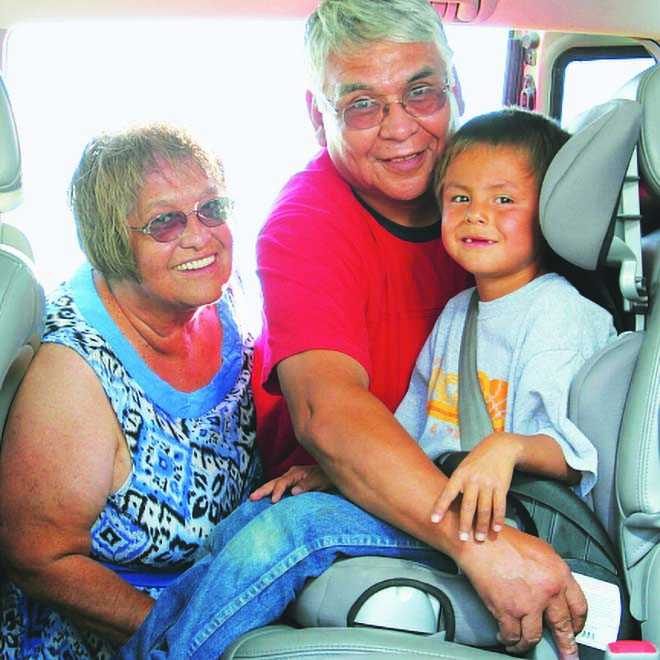A man and woman loading a child into a car seat